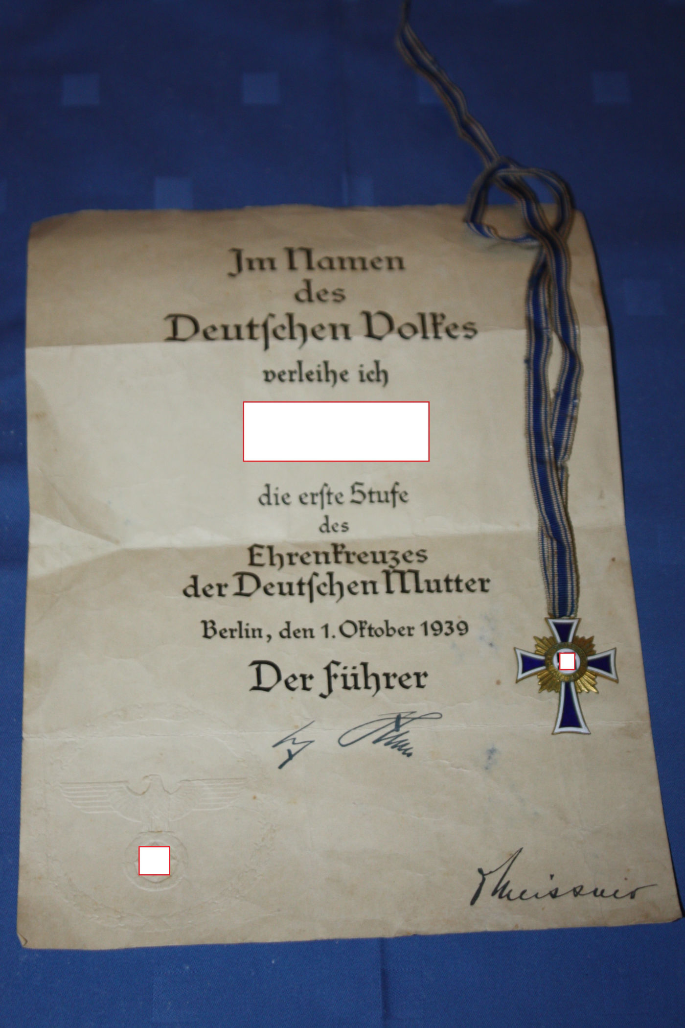 Mutterkreuz in Gold, mit Original Din-A4 Urkunde, 1. Stufe für 8 Kinder, mit blau-weissem Halsband, Emaille an der rechten unteren Ecke bestossen